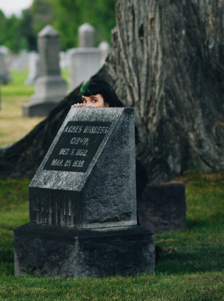 Rene peeks out from behind a gravestone.